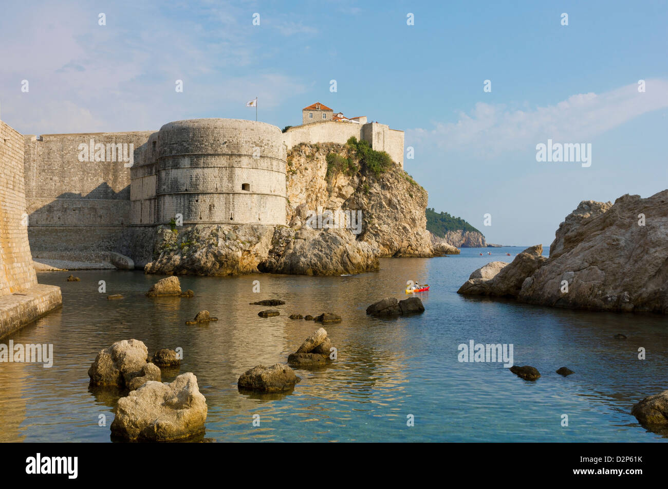 Vista estiva delle vecchie mura della città di Dubrovnik Croazia con una tranquilla e pacifica superficie di acqua in una luminosa giornata di sole. Foto Stock