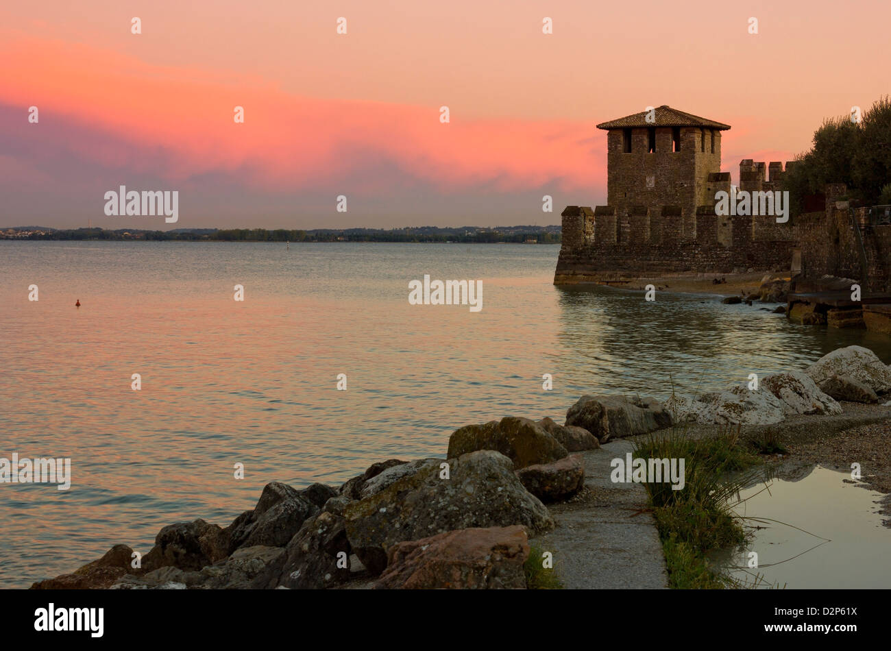 Lago di Garda vista in Sirmione, Italia con caldo tramonto rosso e la torre del castello scaligero nella distanza. Foto Stock