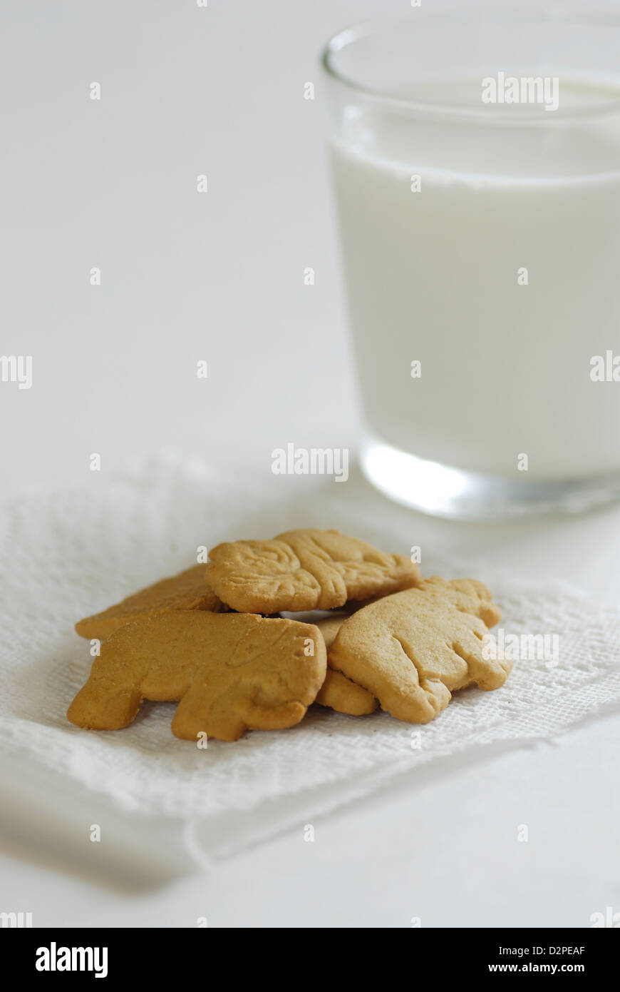 Animal crackers con un bicchiere di latte di mucca su un foglio di carta bianca igienico Foto Stock