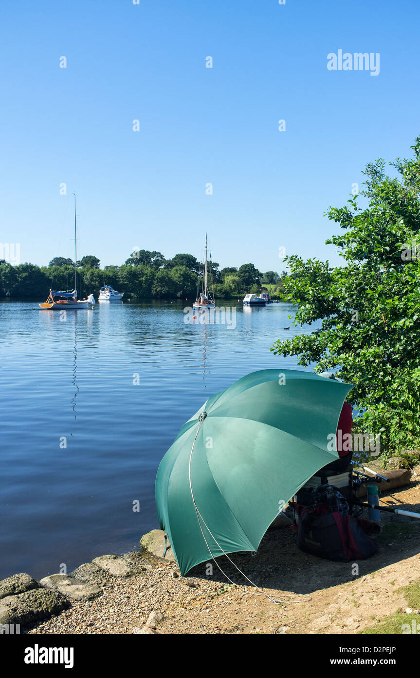 Pescatore seduto sotto Ombrello verde a Wroxham ampia Norfolk Foto Stock