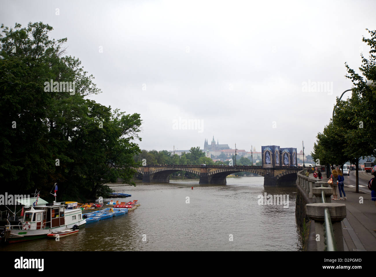 Le barche costeggiano il fiume Moldava con vista su un ponte storico a Praga, Repubblica Ceca, in una giornata coperta. Foto Stock