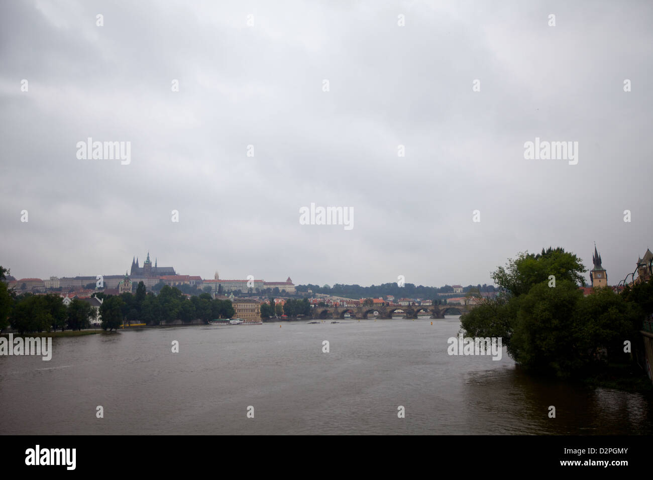 L'iconico Ponte Carlo di Praga e il Castello di Praga sono stati visti attraverso il fiume Moldava in una giornata nuvolosa, mostrando la ricca storia e l'architettura della città Foto Stock