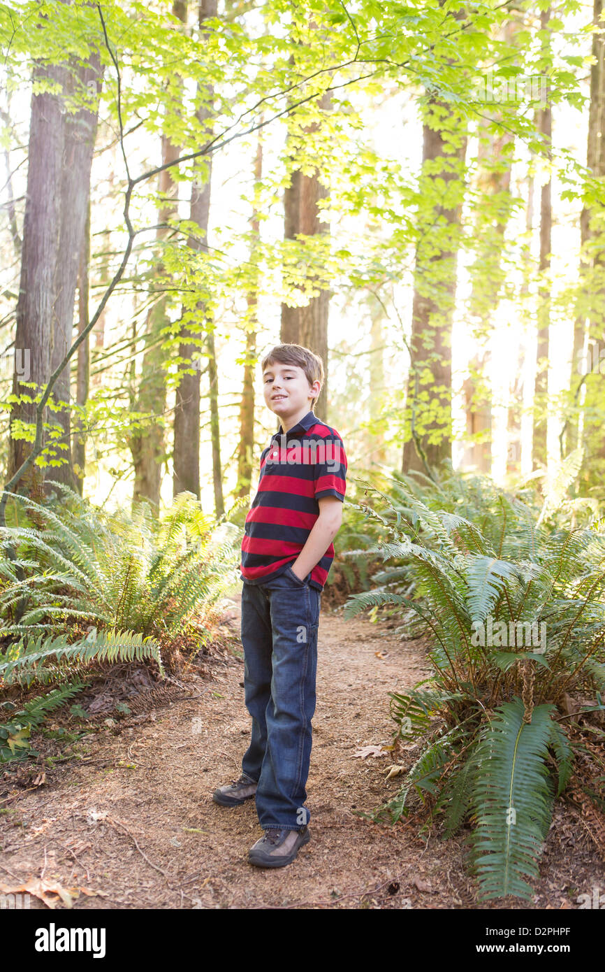 Ragazzo caucasico in piedi sul percorso nel bosco Foto Stock