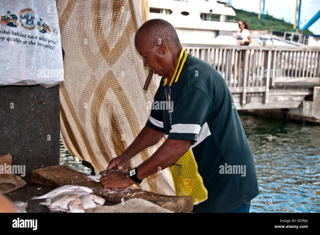 L'uomo la scalabilità e la pulizia del pesce al mercato galleggiante, Willemsatd Curacao Foto Stock