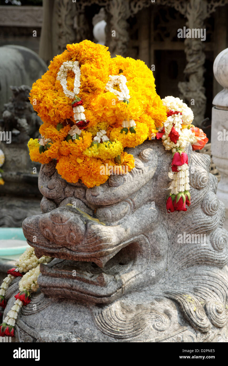Ghirlanda di fiori su un leone di pietra statua Foto Stock