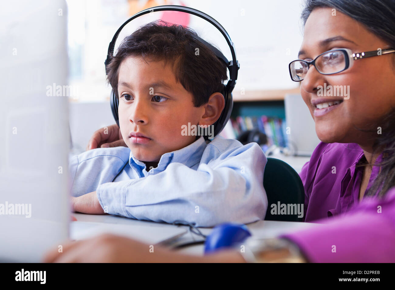 Insegnante aiutando studente utilizzando laptop in aula Foto Stock