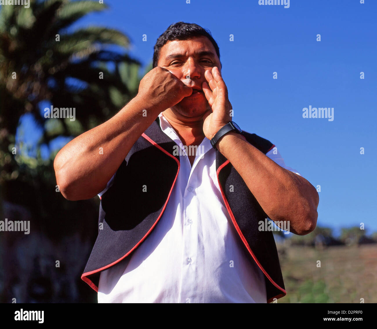 Uomo che dimostra la lingua fischiata nel paesaggio della valle, la Gomera, Isole Canarie, Spagna Foto Stock