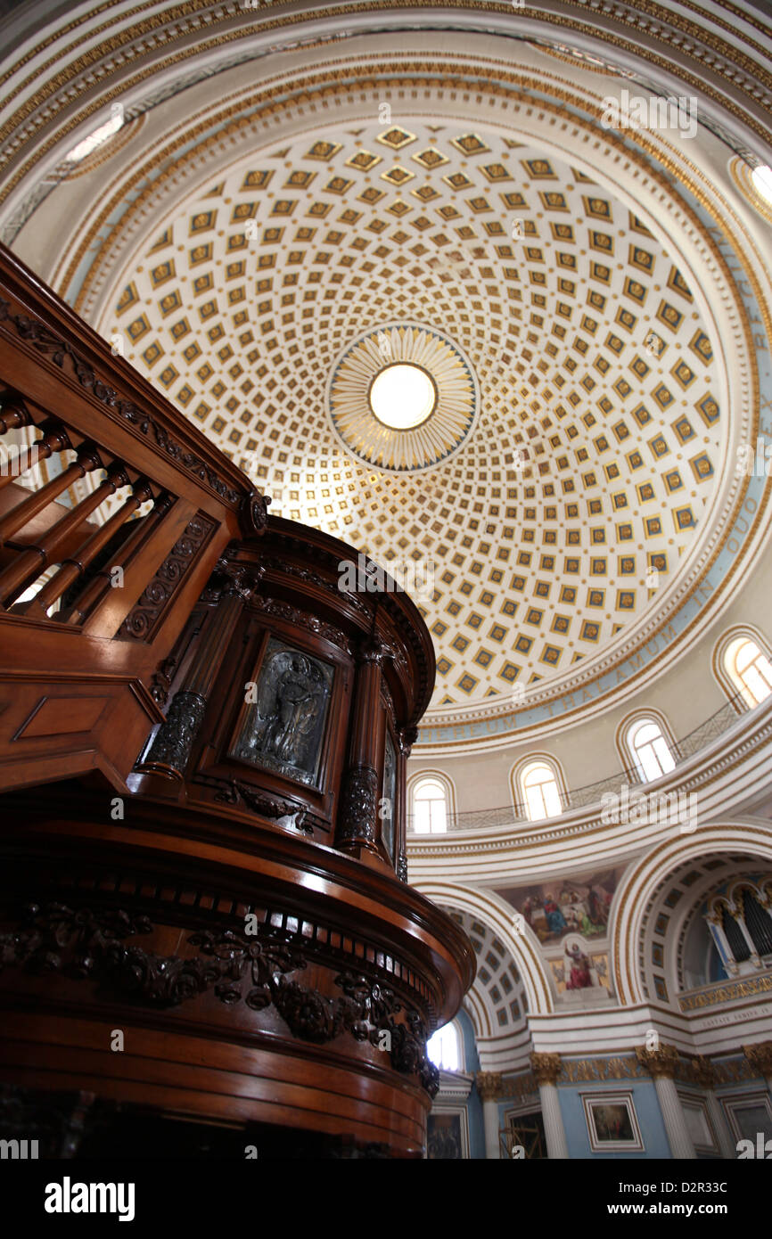 Un riccamente intagliato pulpito in legno e il duomo di Mosta soffitto interno in background Foto Stock