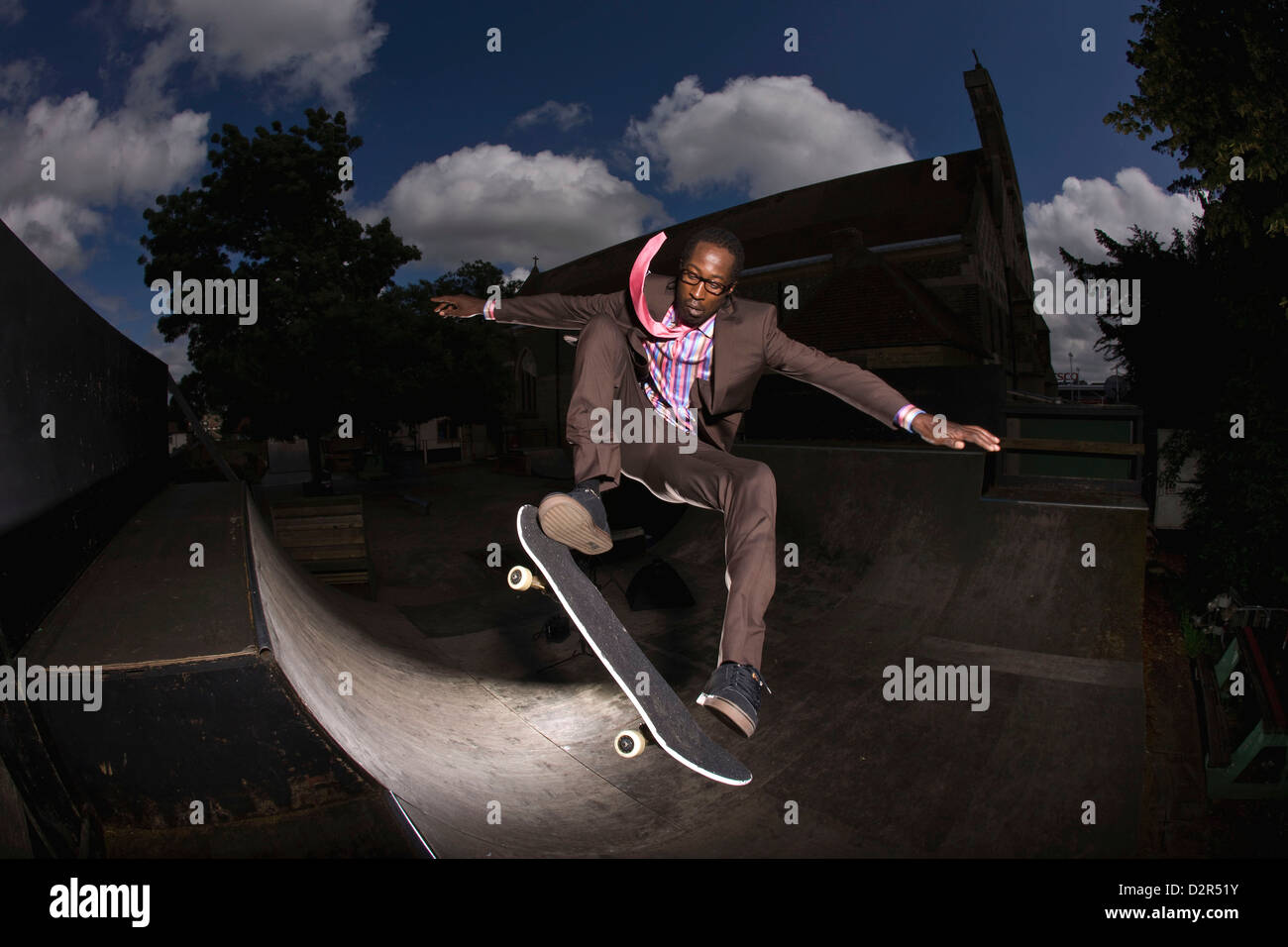 Guidatore di skateboard in tuta sulla rampa, metà azione aria stunt Foto Stock