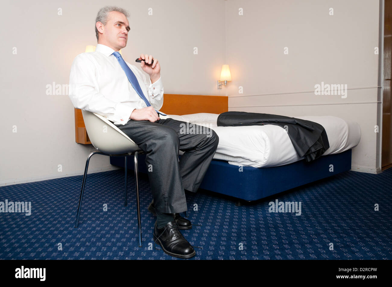 Business uomo seduto da solo nella camera di albergo. Foto Stock