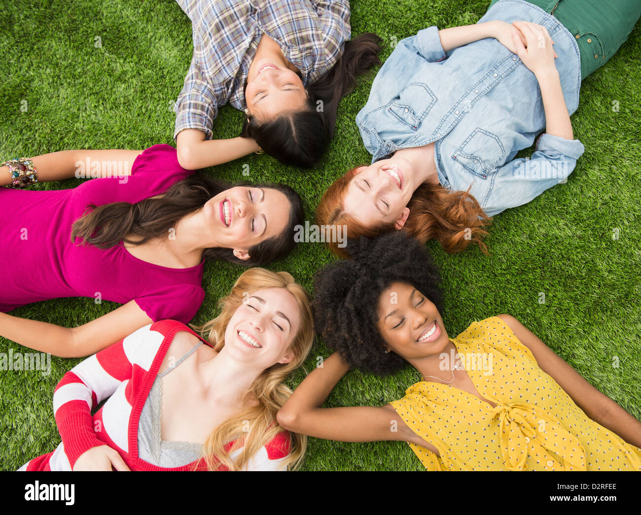 Donna sorridente posa in erba insieme Foto Stock