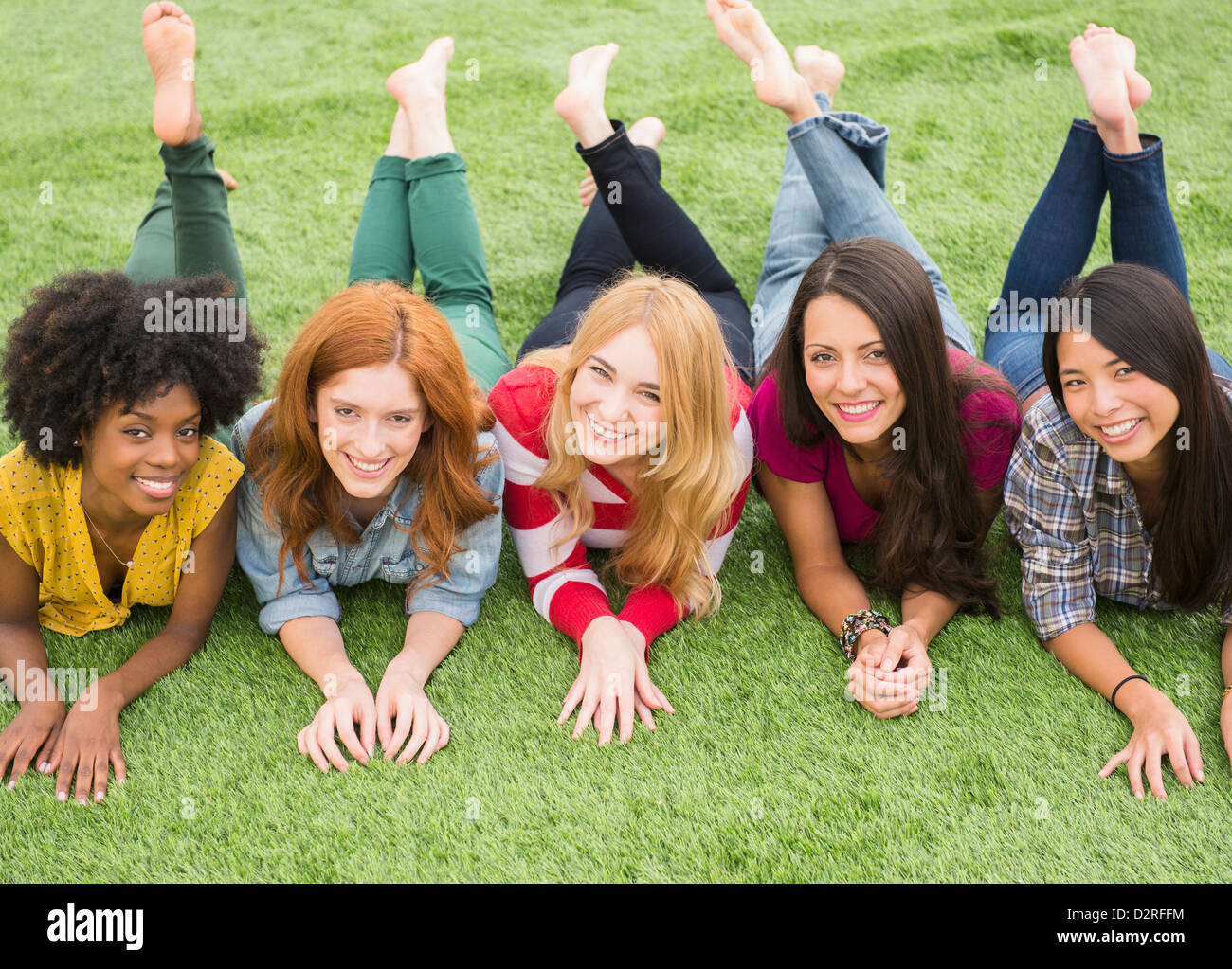 Donna sorridente posa in erba insieme Foto Stock