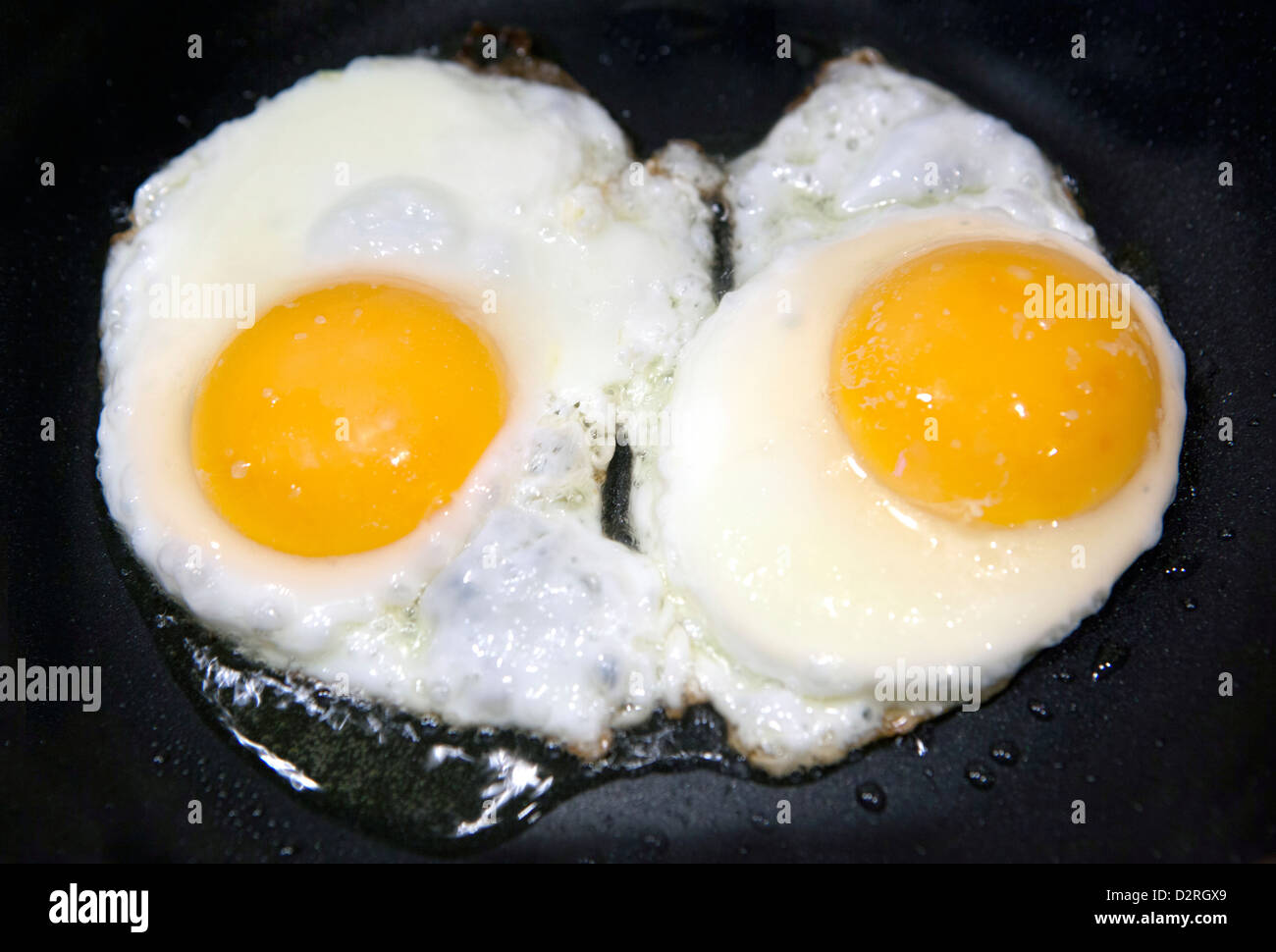 Due uova fritte su sfondo nero Foto Stock
