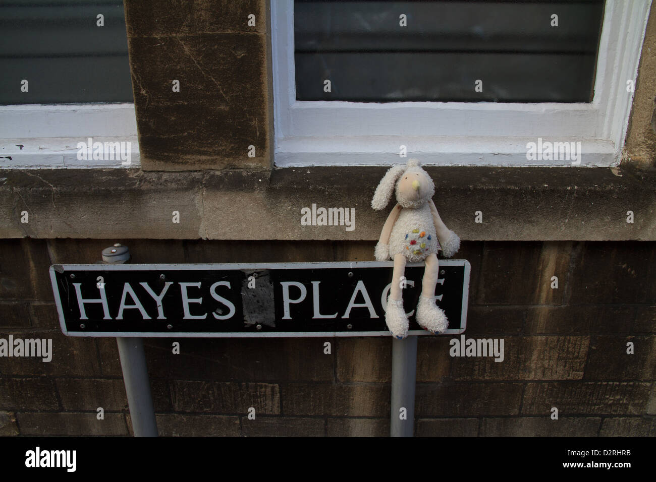 Un perse o abbandonate del bambino giocattolo di coniglio siede su un cartello stradale a Hayes Place, bagno, Somerset Foto Stock