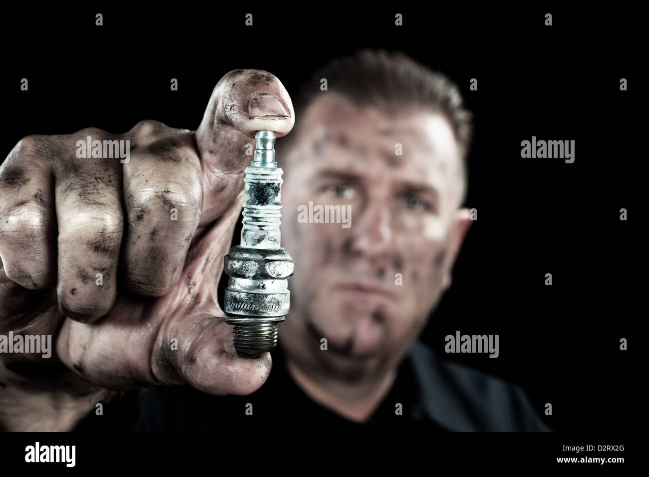 Un meccanico automatico mostra un danneggiato e usurato candela come egli esegue una messa a punto. Foto Stock