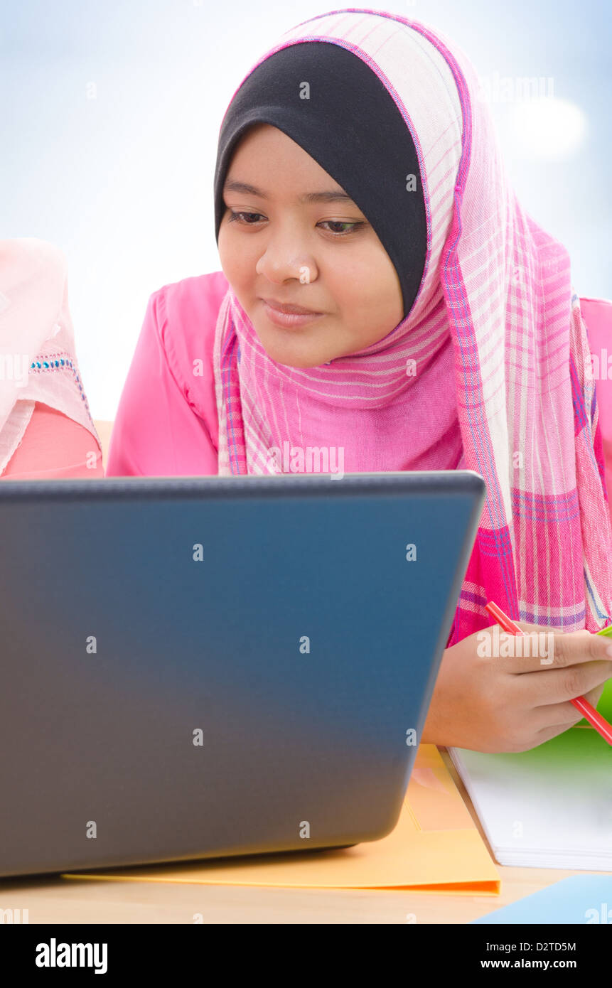 Ragazze musulmane. Sud-est asiatico college musulmano ragazze discutere, cercando su schermo portatile, indoor. Foto Stock
