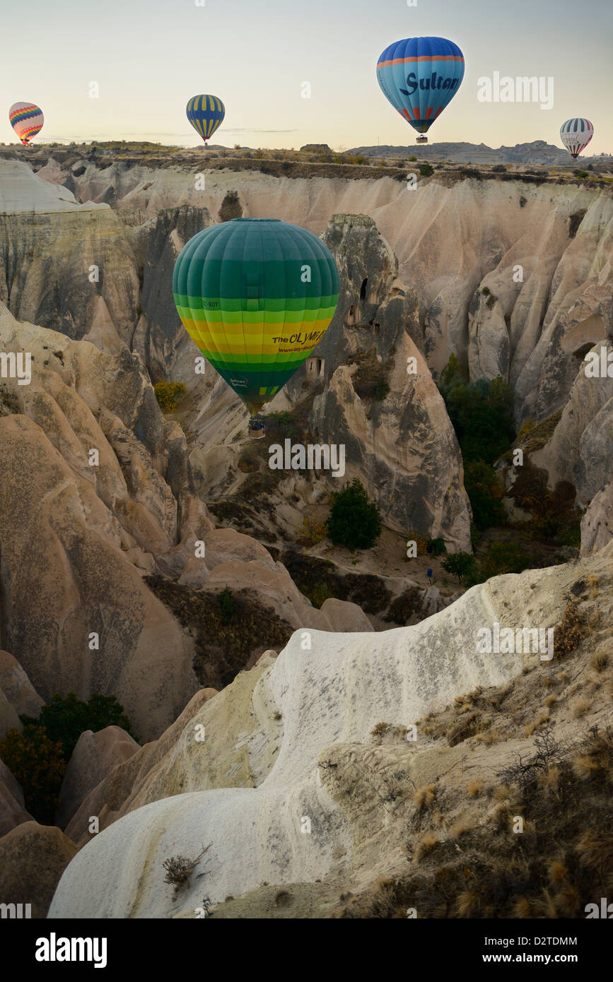 I palloni ad aria calda su un ripido canalone di eroso tufo vulcanico e cave houses in Cappadocia Turchia Foto Stock
