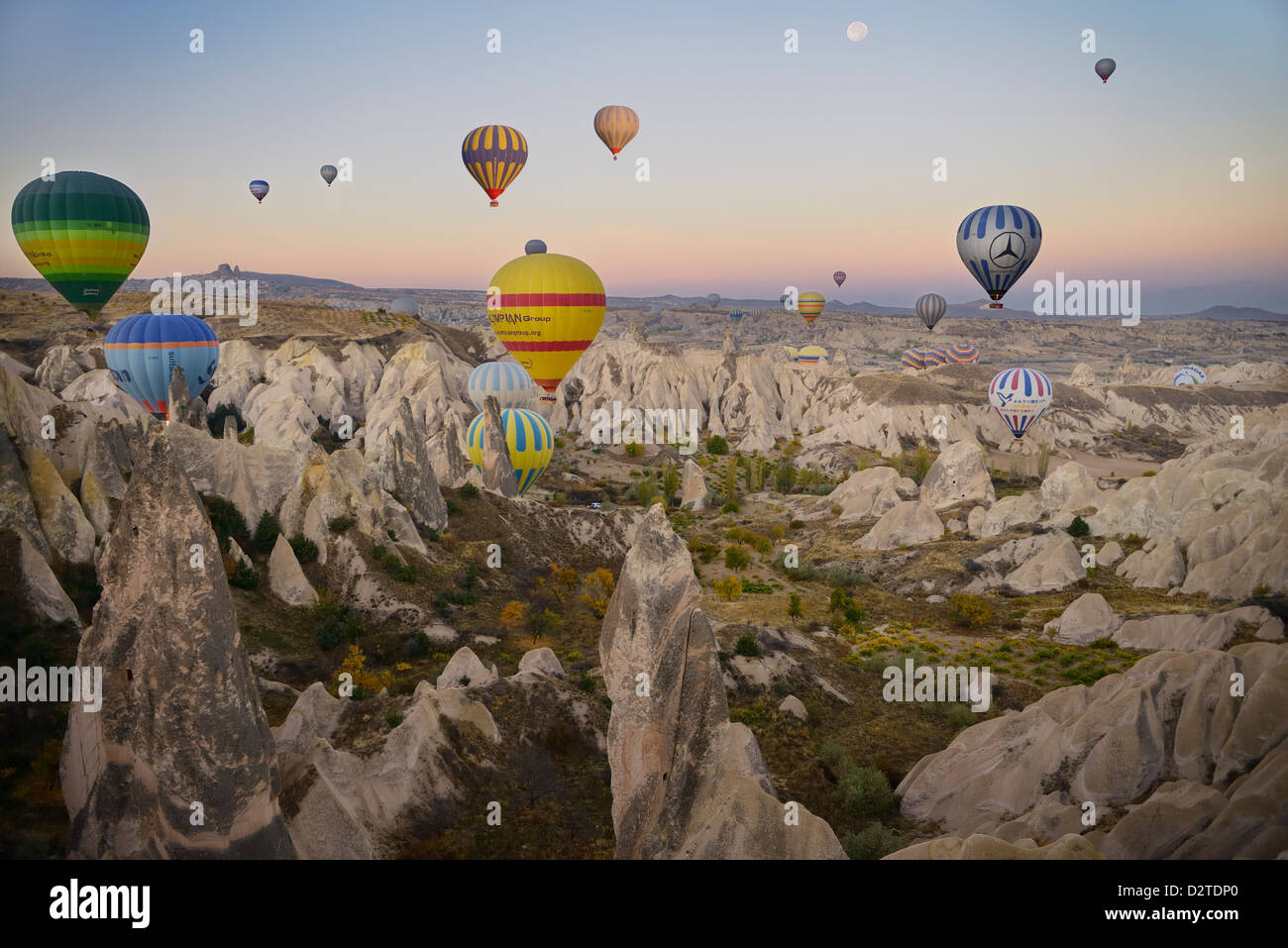 Molti i palloni ad aria calda sopra la valle rossa cappadocia Turchia all'alba con la luna Foto Stock