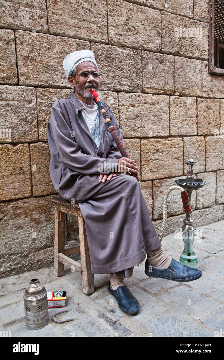 Un vecchio uomo fuma sheesha in Khan el-Khalili bazaar del Cairo, Egitto. Versione Mono disponibile in D2GX11 Foto Stock