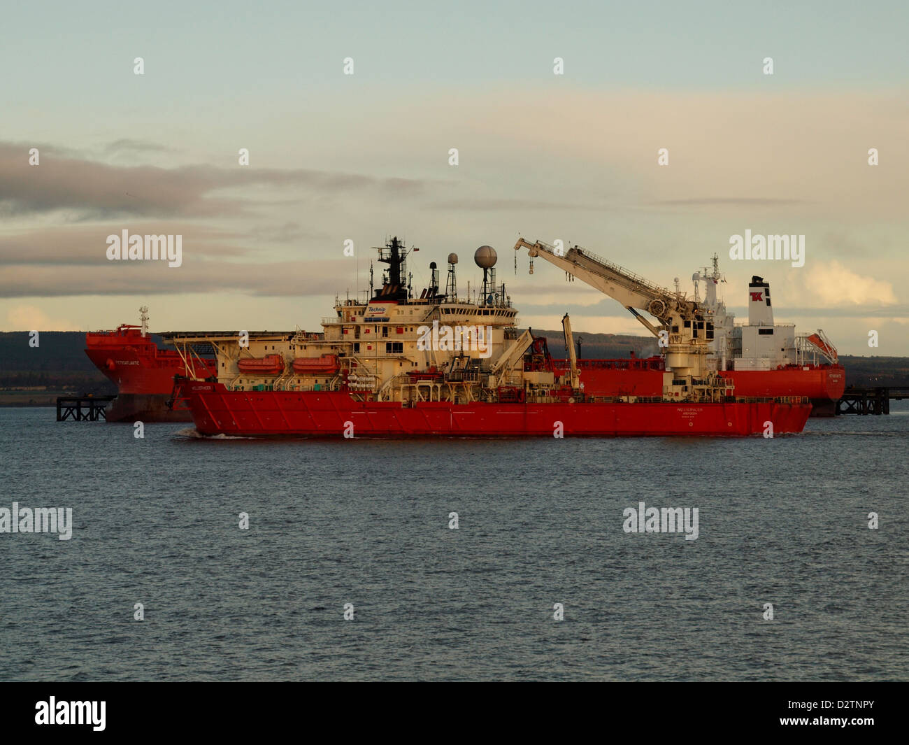 Un Mare del Nord costruzione nave passa una petroliera al Nigg terminale petrolifero, sulla rotta per Invergordon Foto Stock