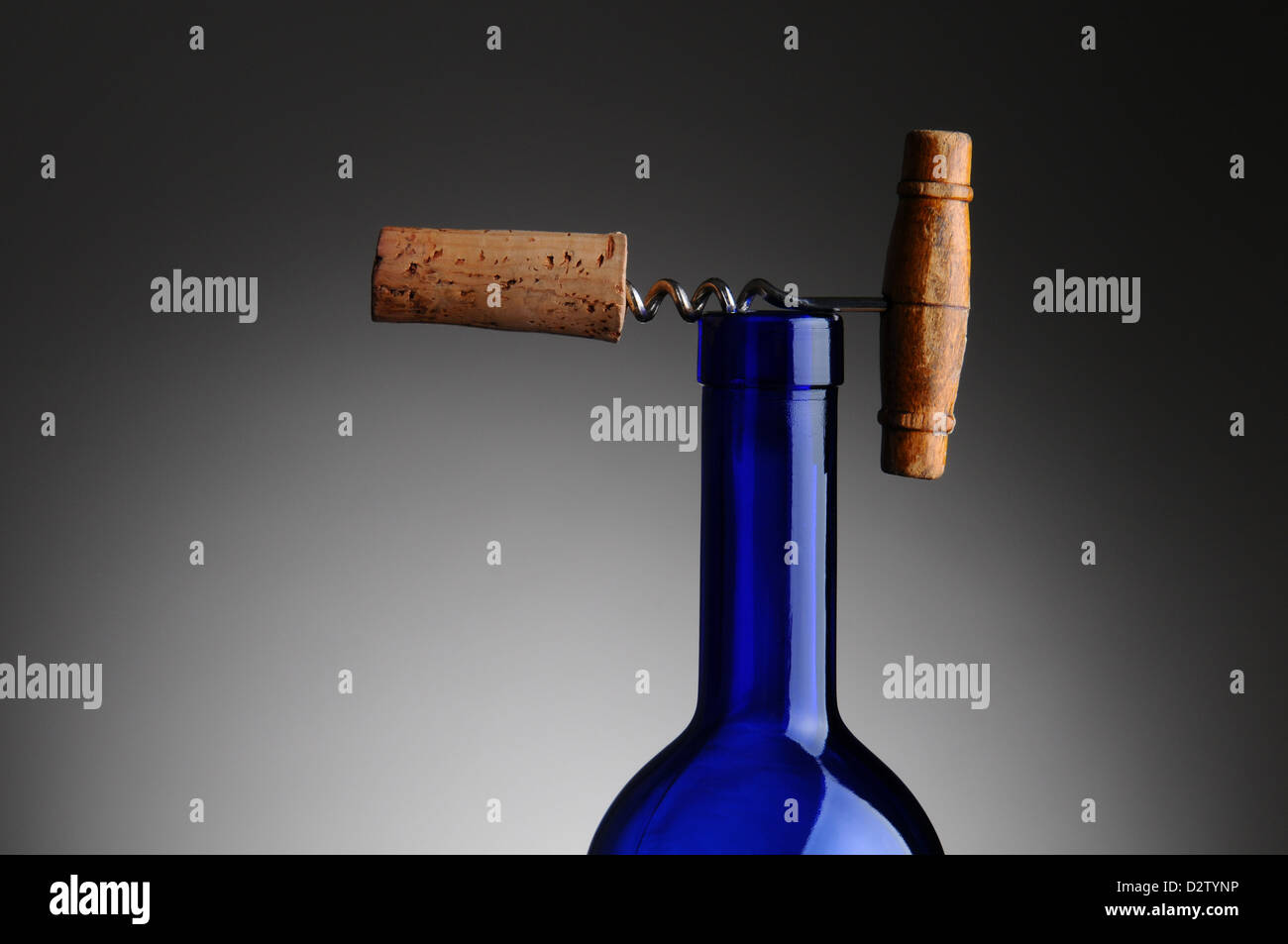 Primo piano di una antica struttura di cavatappi con sughero fissata in appoggio sulla parte superiore di un blu bottiglia di vino. Foto Stock
