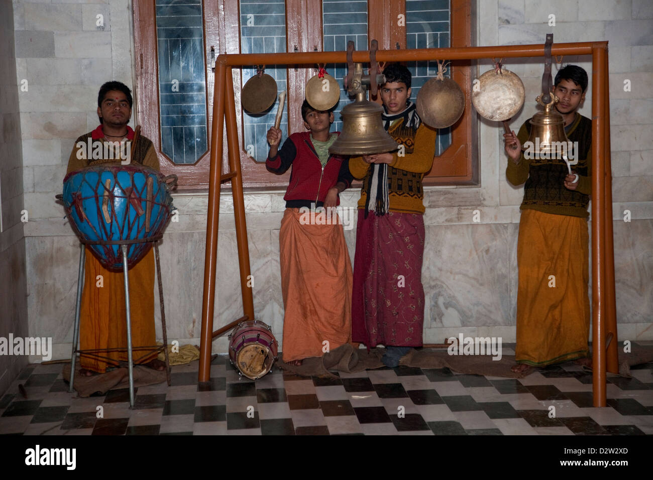 India, Rishikesh. Giovani uomini la riproduzione di gong, campane e tamburo in un tempio indù. Foto Stock
