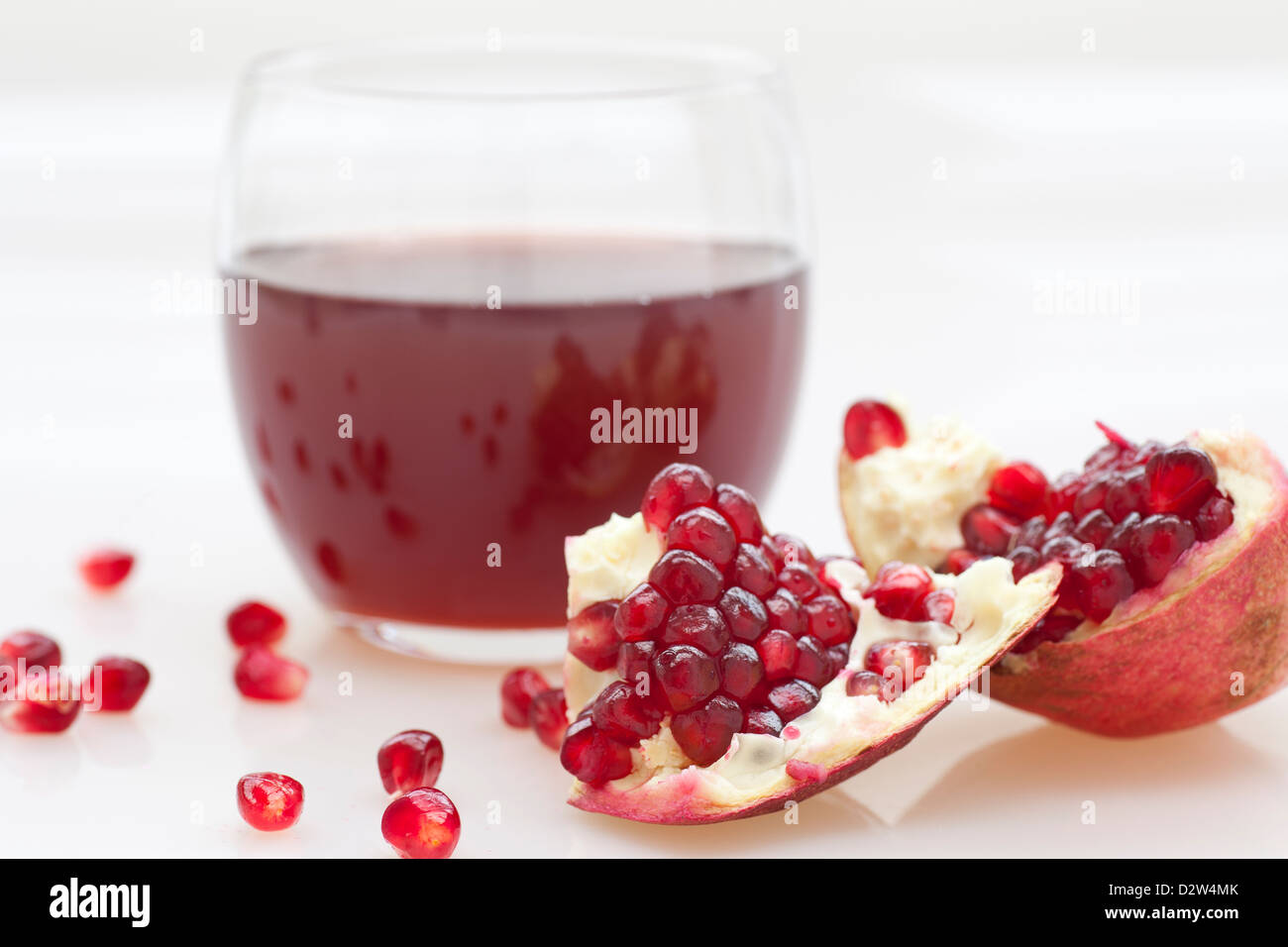 Fresh melograno e bicchiere di succo di frutta sul tavolo bianco. Foto Stock