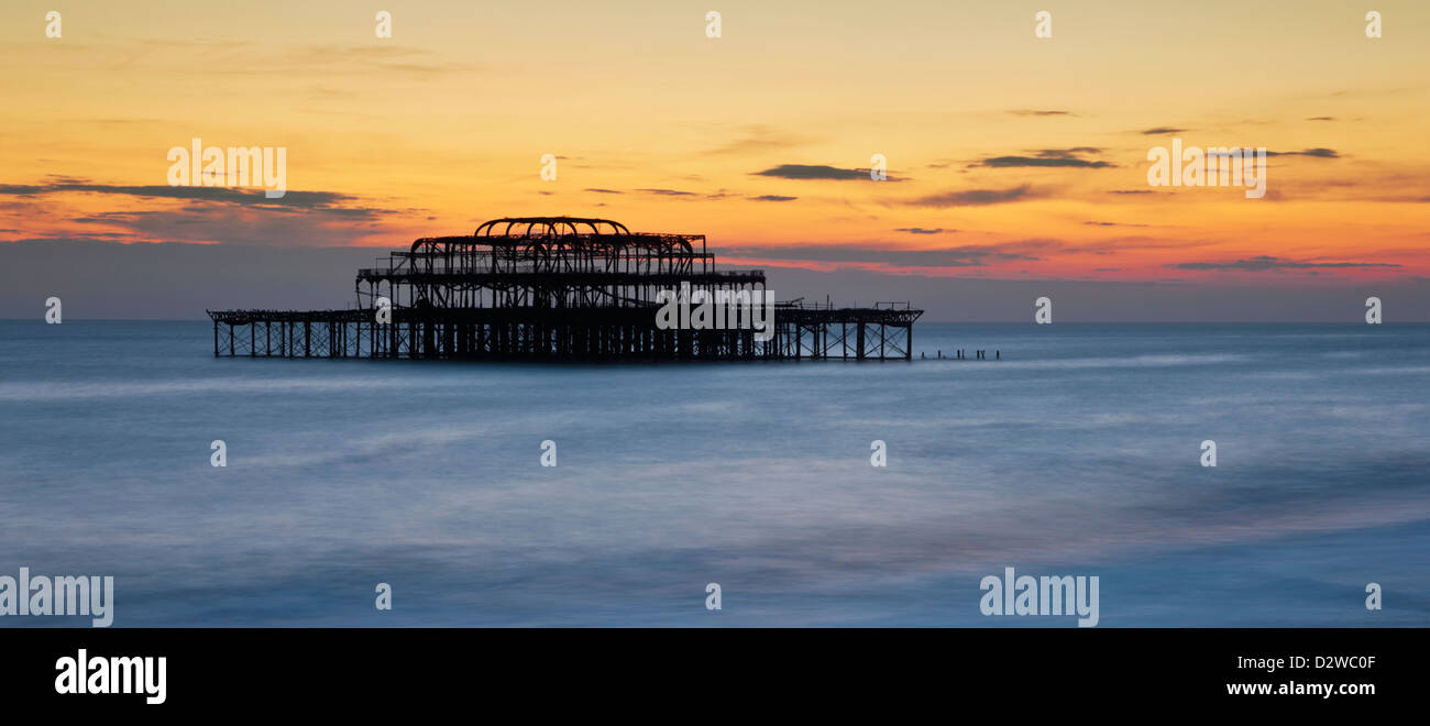 Brighton il bruciato molo Ovest al tramonto in East Sussex, Regno Unito. Foto Stock