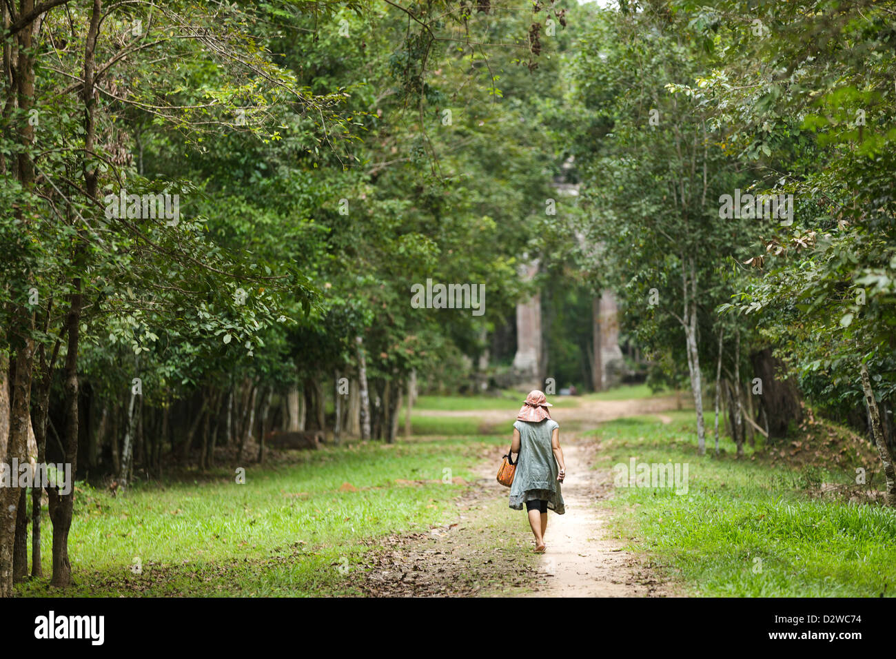 Donna facendo una passeggiata in una strada forestale che conduce a Angkor Thom porta della morte, Cambogia Foto Stock