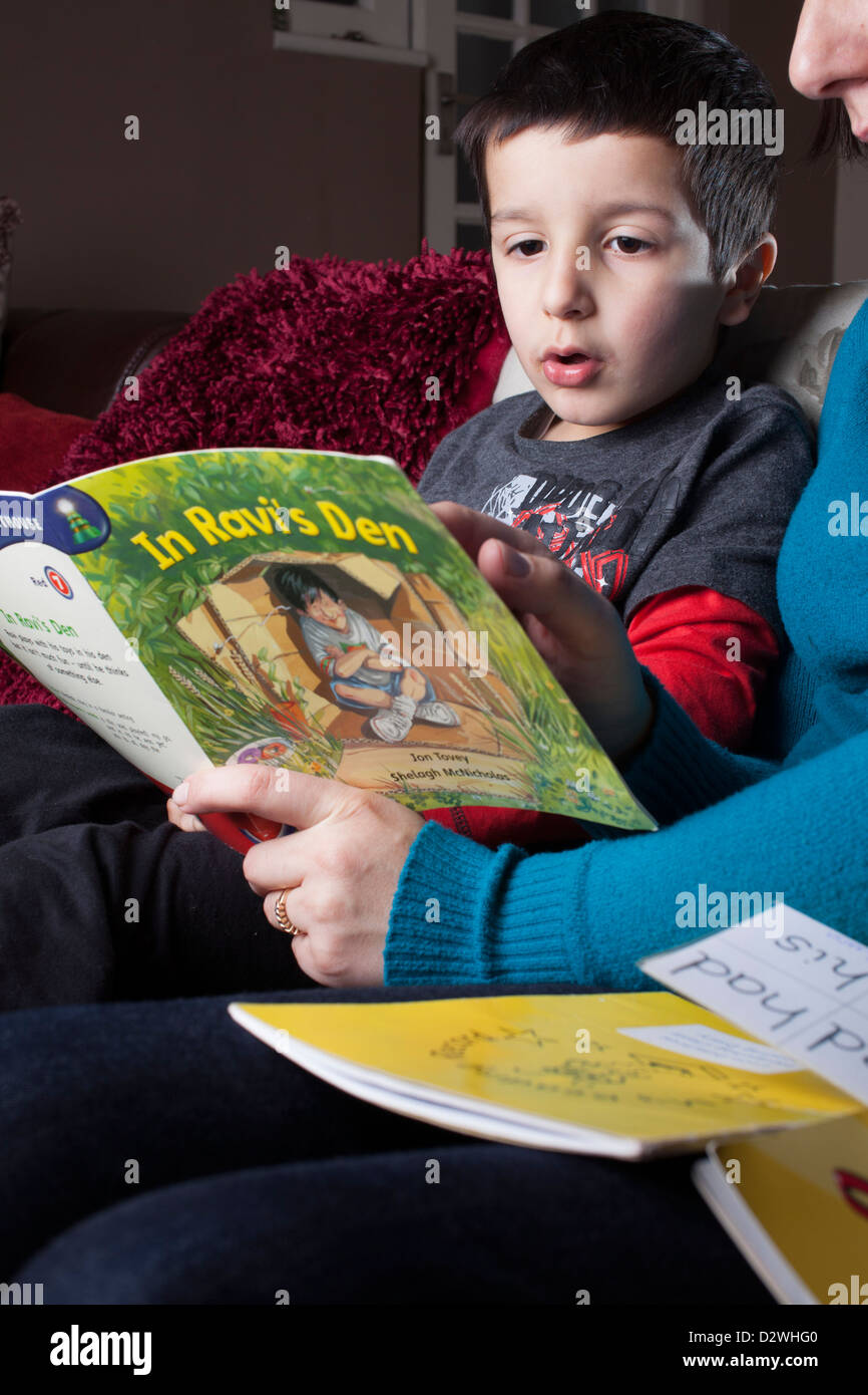Madre aiuta a 5 anni bambino per leggere un libro Foto Stock