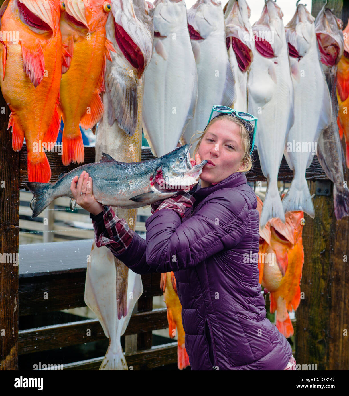 Charter imbarcazione fisher donna baci felicemente il pescato del giorno per la fotocamera, Seward, Alaska, STATI UNITI D'AMERICA Foto Stock