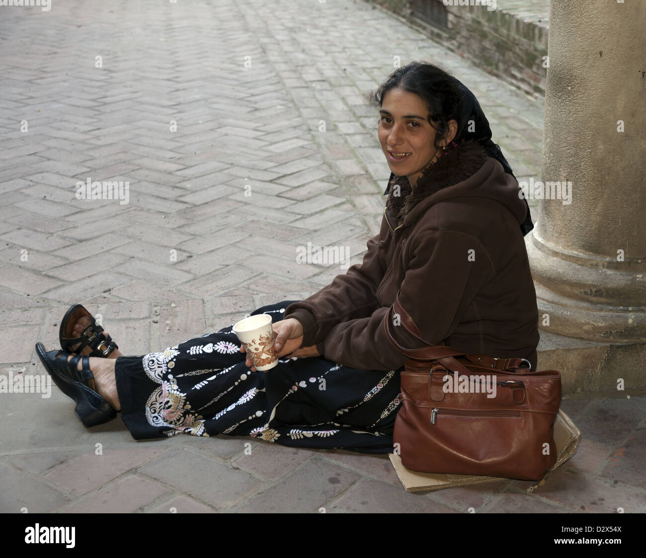 Mendicante femmina con oro tappate denti seduta su cartone azienda bicchiere di carta per raccogliere denaro Malaga Spagna Foto Stock