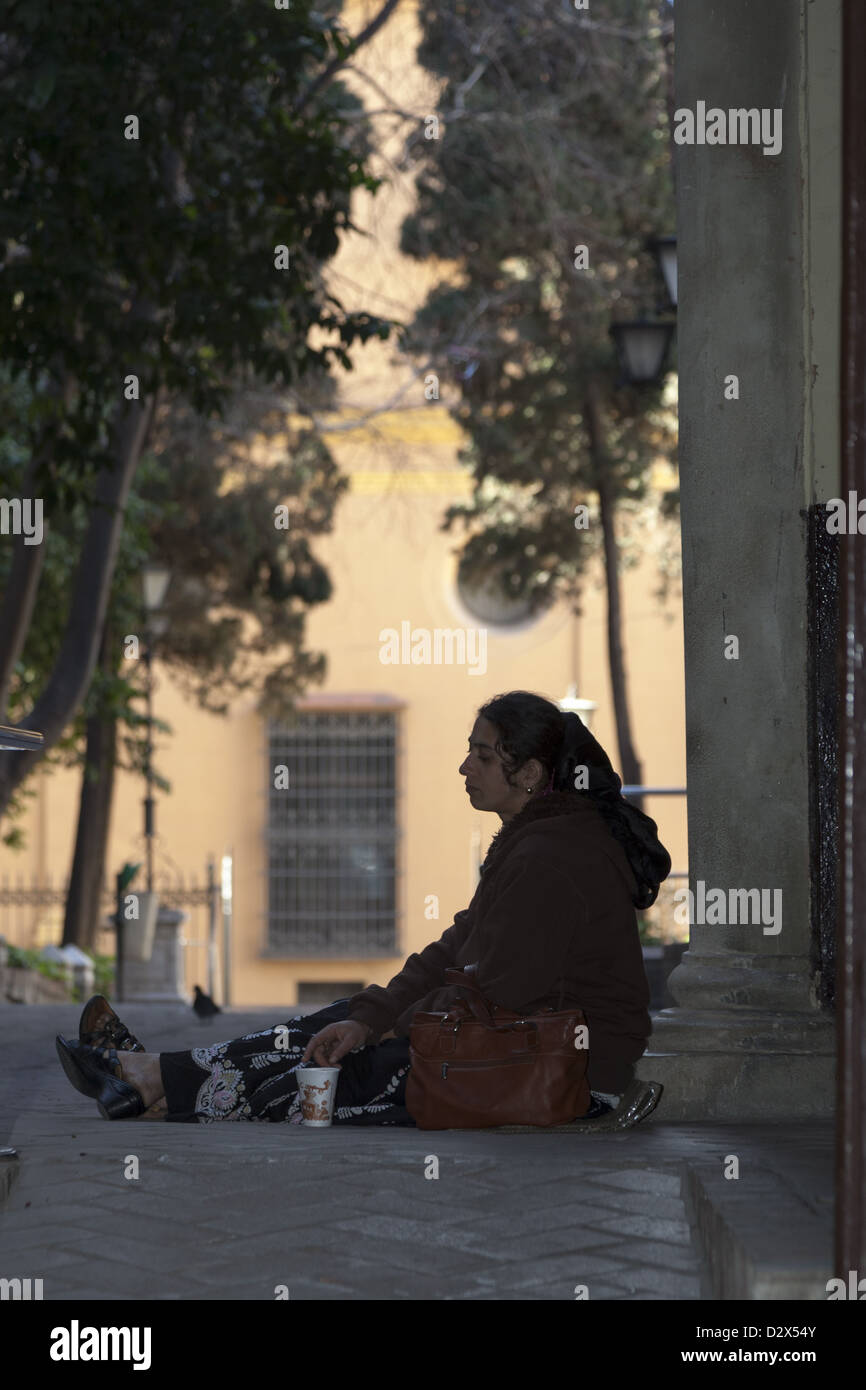 Mendicante femmina seduto su cartone azienda bicchiere di carta per raccogliere fondi nel passaggio di Malaga Spagna Foto Stock