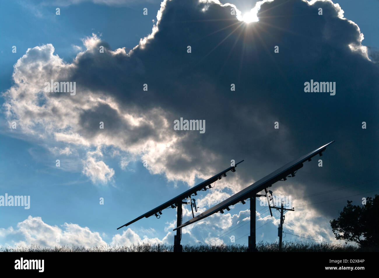 Sun che emergono da dietro dark cloud su pannelli solari Foto Stock