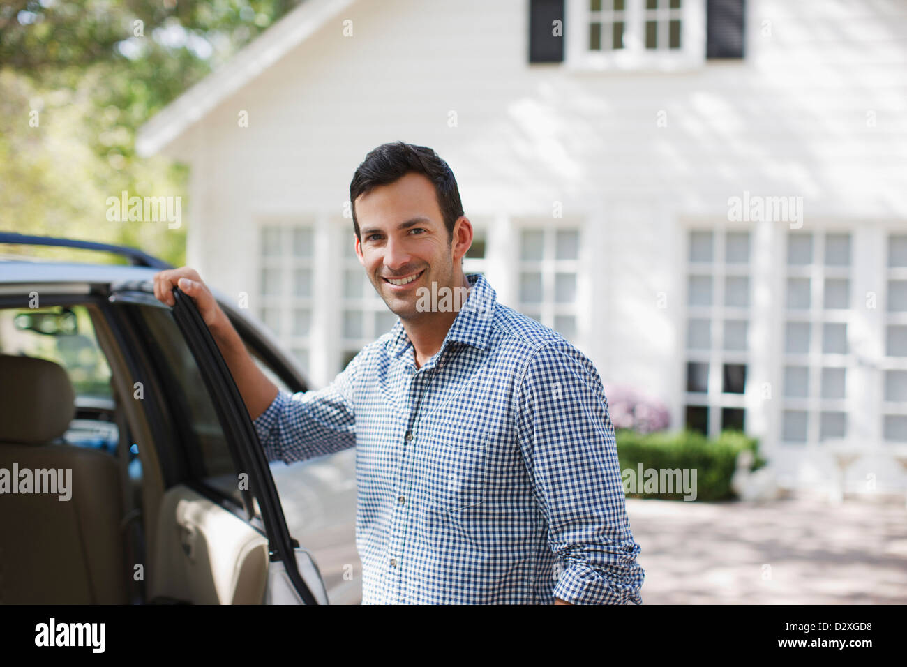 Uomo sorridente apertura porta auto Foto Stock