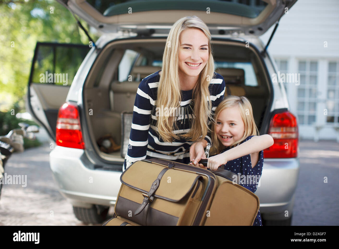 Madre e figlia che trasportano bagagli per auto Foto Stock