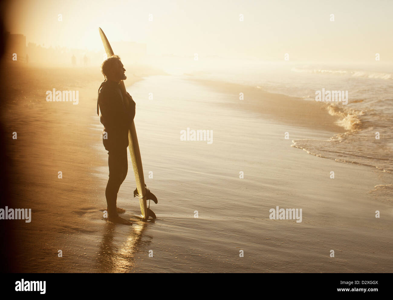 Surfer in piedi con la scheda sulla spiaggia Foto Stock