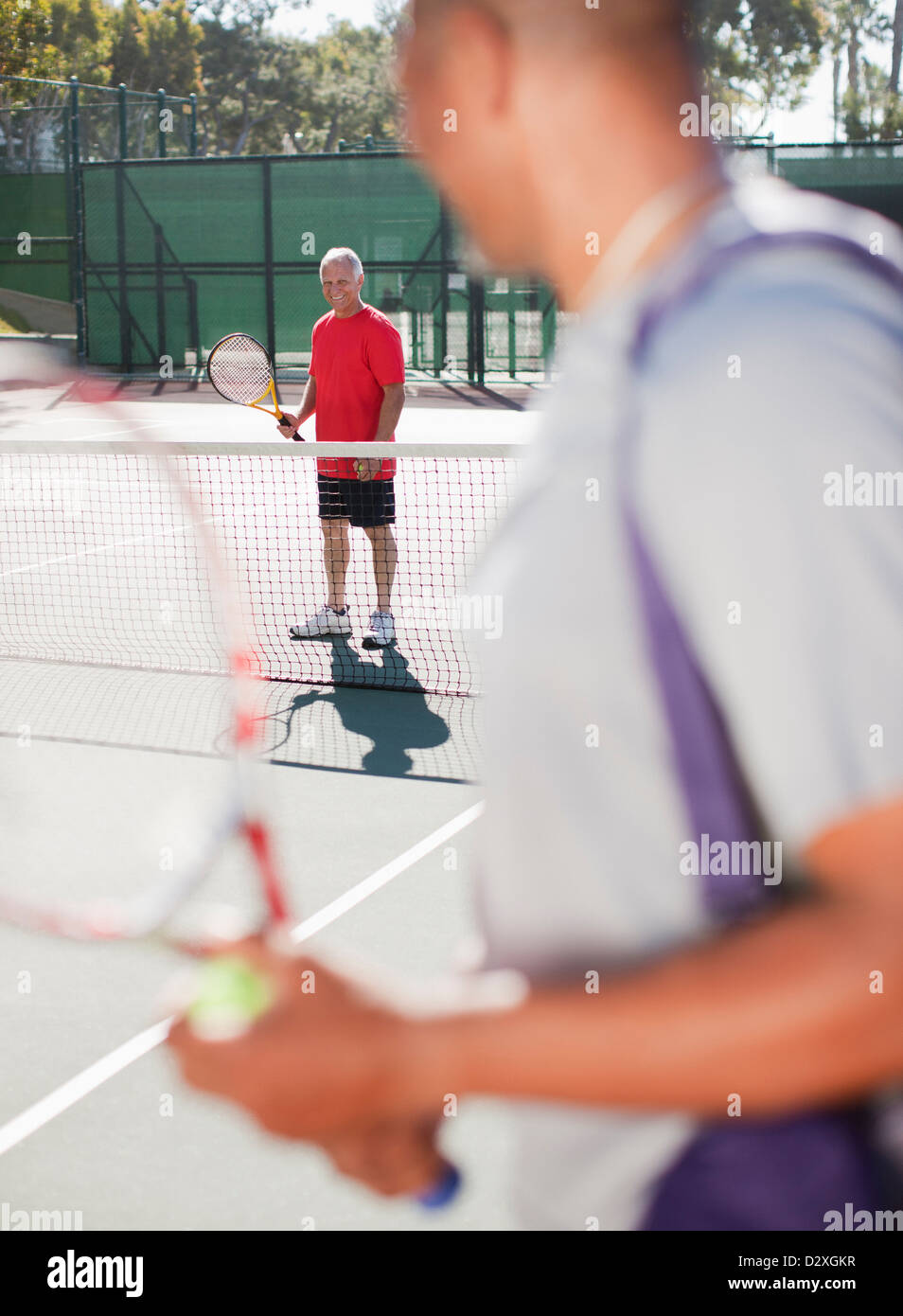 Gli uomini più anziani a giocare a tennis su corte Foto Stock