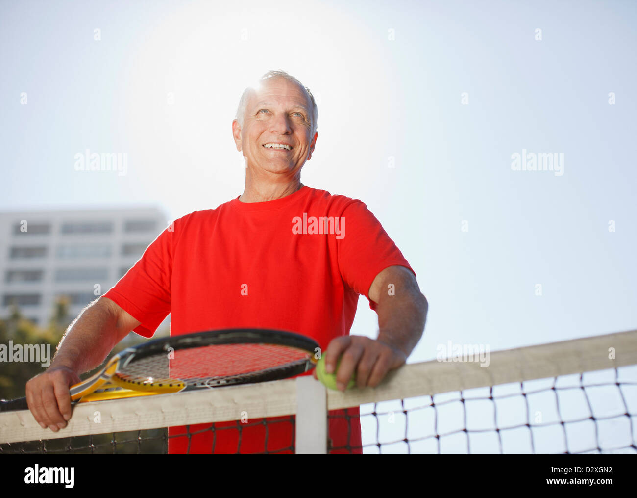 Uomo anziano giocando a tennis su corte Foto Stock