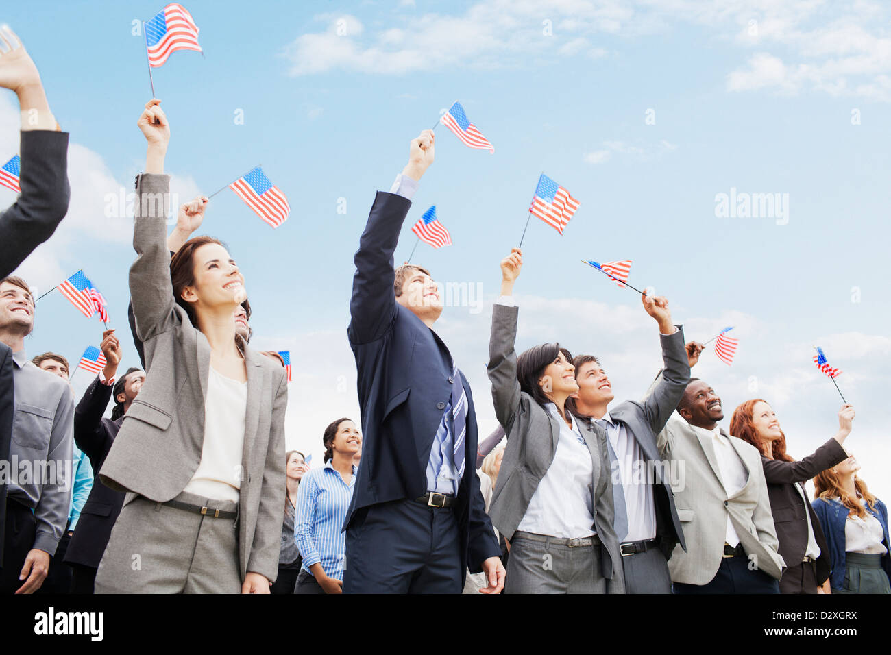 Sorridente la gente di affari in folla sventolando bandierine americane Foto Stock