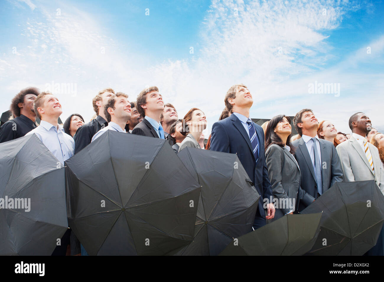 La folla di gente di affari con ombrelloni guardando il cielo Foto Stock