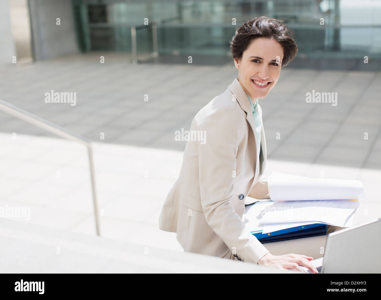 Ritratto di imprenditrice sorridente con notebook e documenti al di fuori di edificio Foto Stock