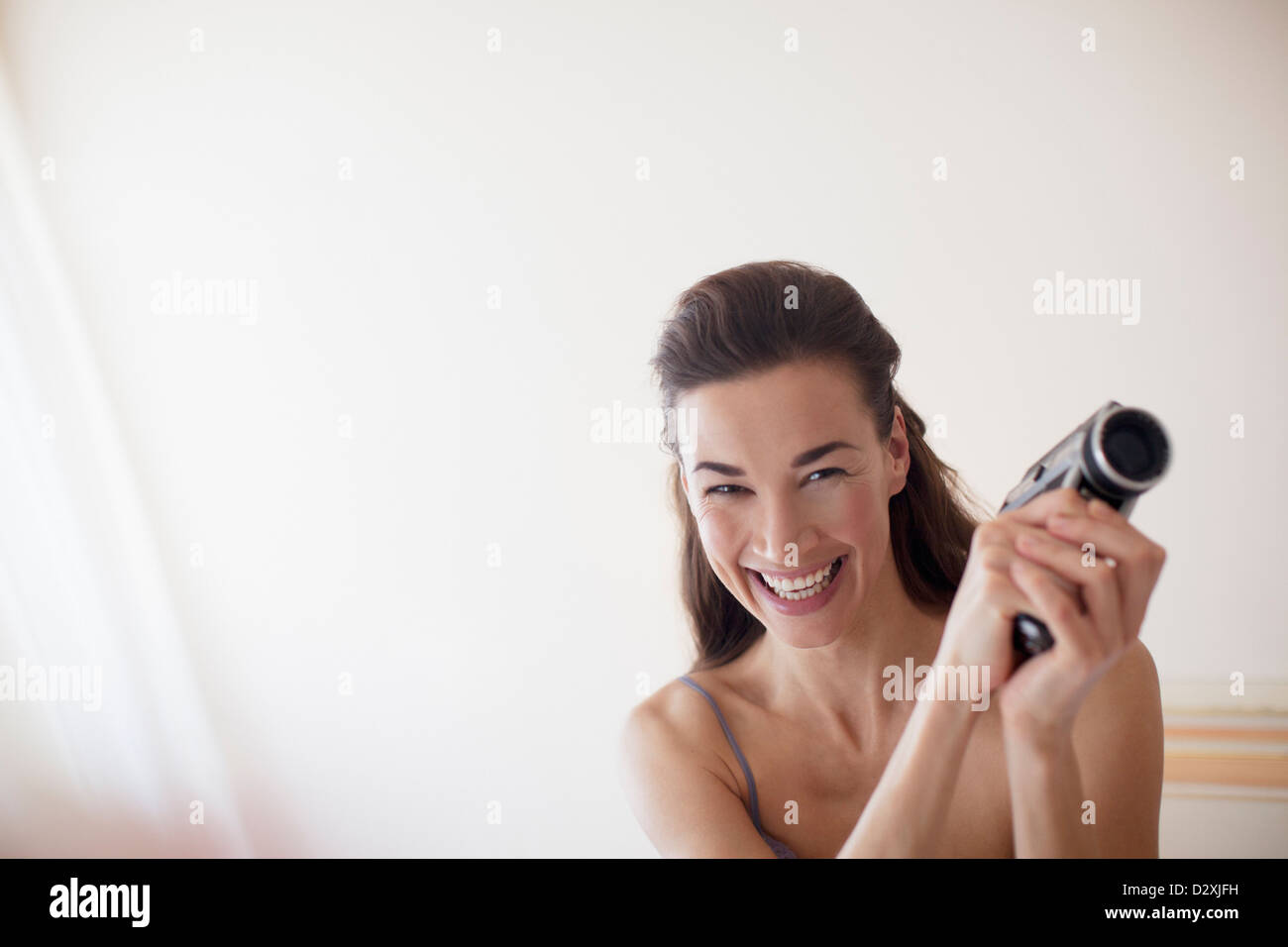 Ritratto di donna sorridente con videocamera in camera da letto Foto Stock