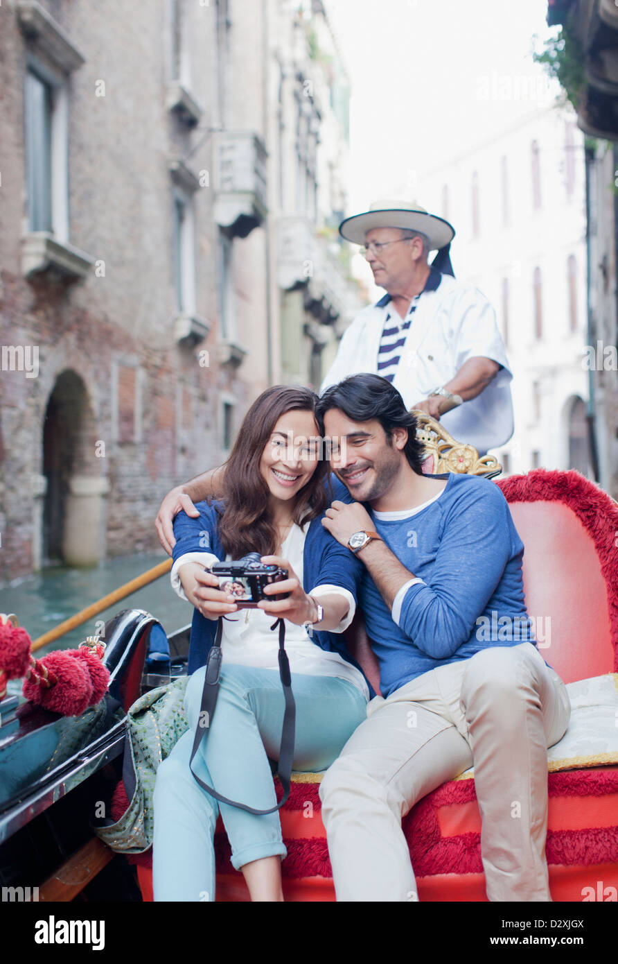 Coppia sorridente tenendo autoritratto con fotocamera digitale in gondola sul Canal a Venezia Foto Stock
