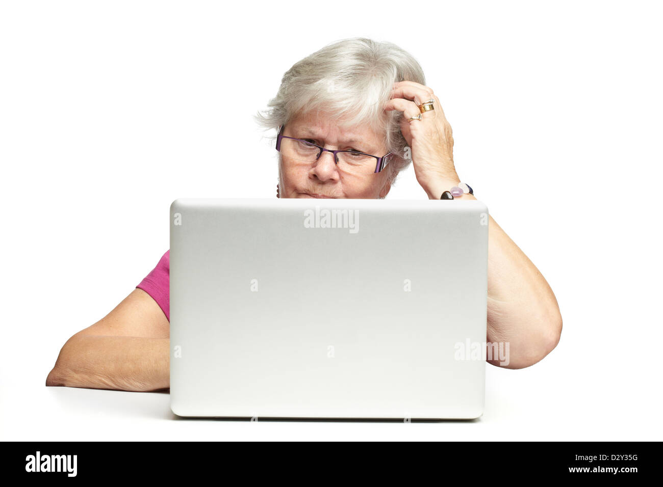 Senior donna utilizzando portatile mentre cercando confuso, su sfondo bianco Foto Stock