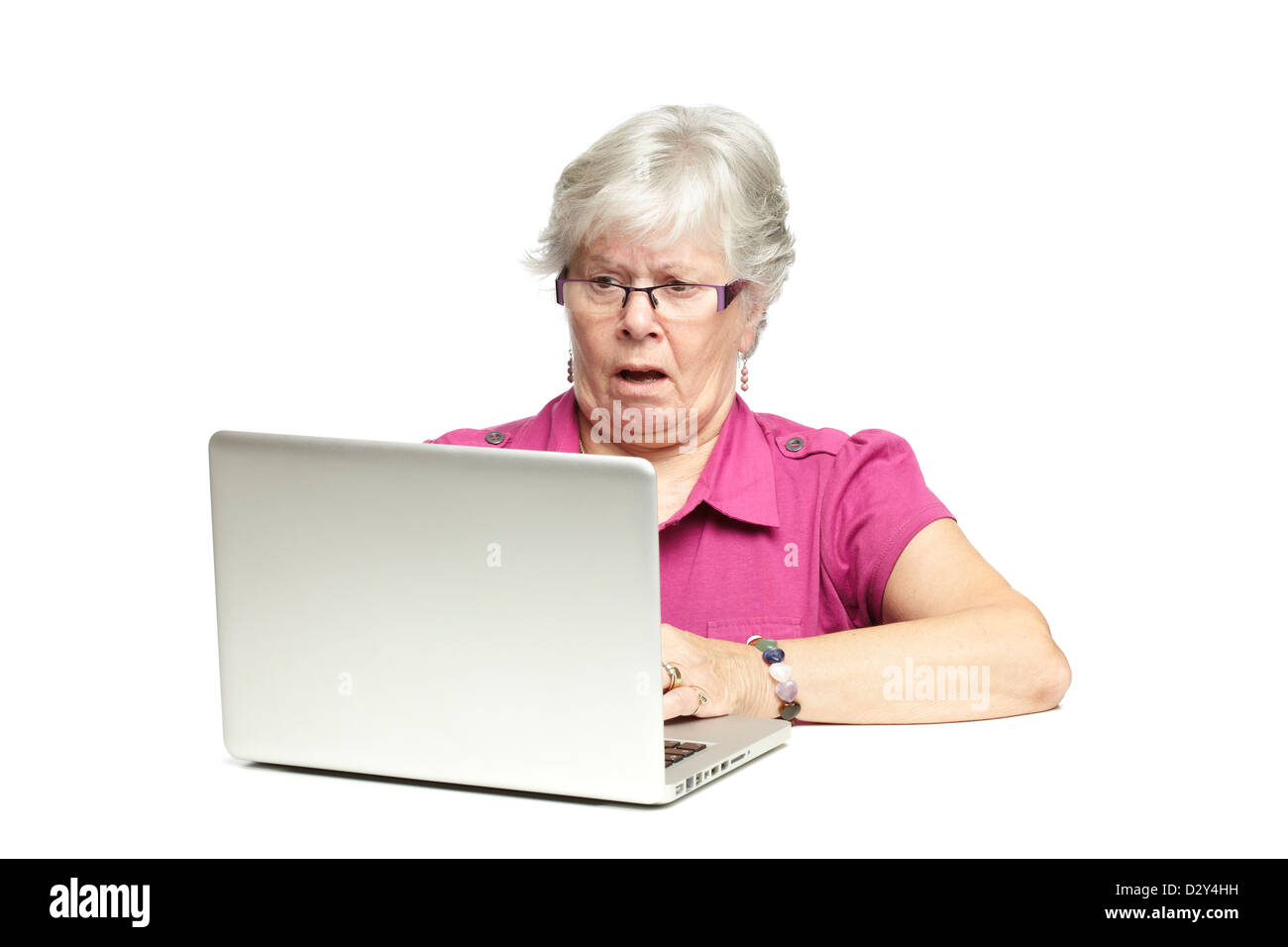 Senior donna utilizzando portatile mentre guardando scioccato, su sfondo bianco Foto Stock