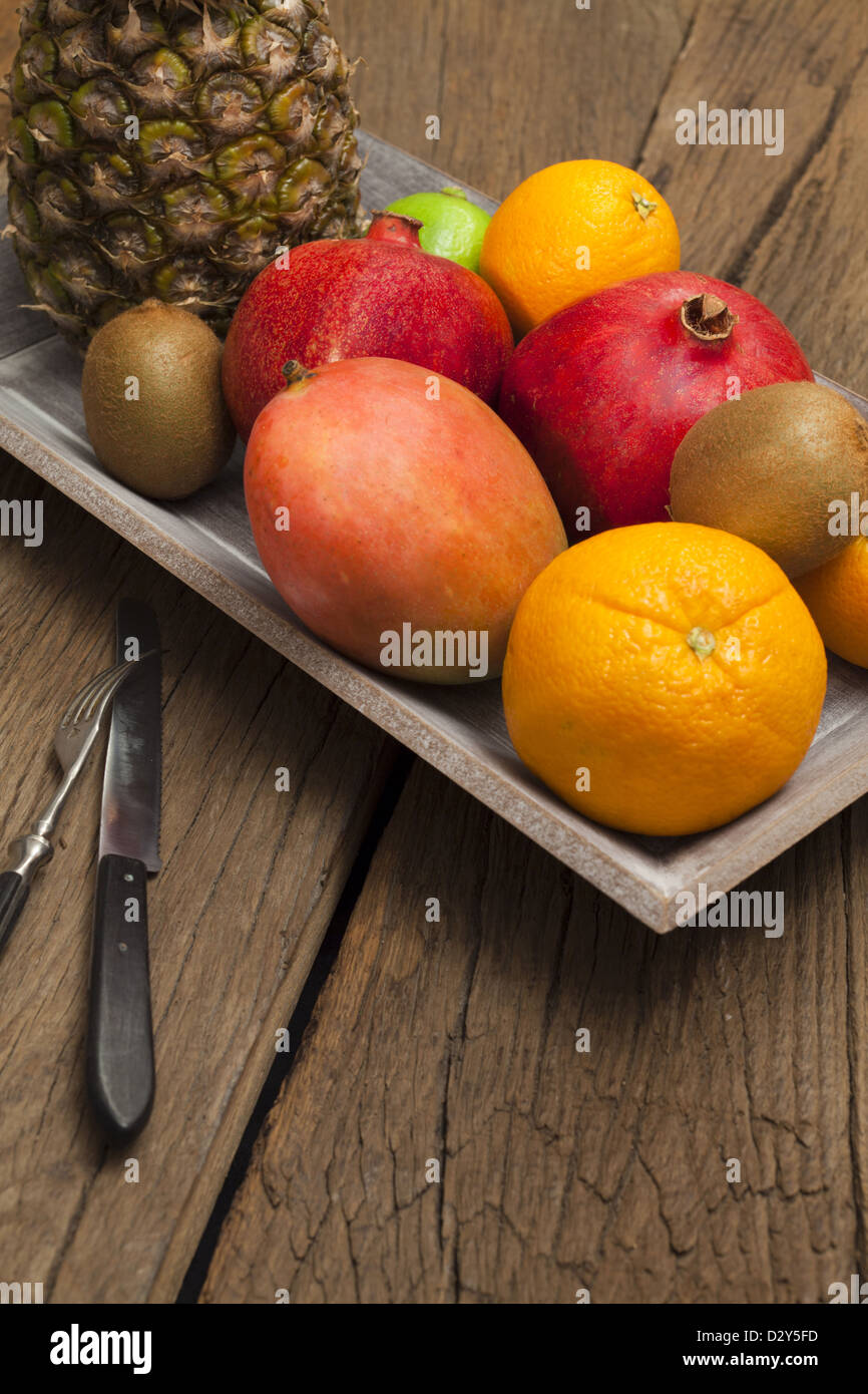 Ciotola di legno con frutta e un coltello con la forcella su un vecchio tavolo in legno Foto Stock