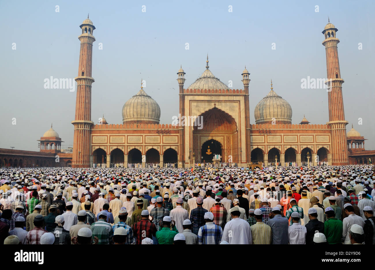 Migliaia di gente musulmana seduta all'interno e al di fuori della moschea. Celebrare la fine del Ramadan. Foto Stock