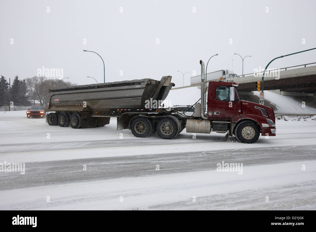 Trasporto merci di grandi dimensioni carrello carico di traino su strada gelata in caduta di neve Saskatoon Saskatchewan Canada Foto Stock