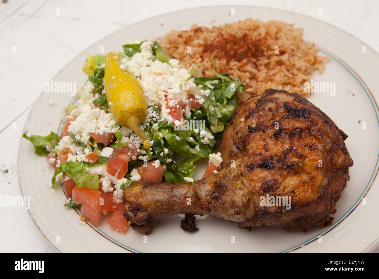 Piastra di stile Mediterraneo cena con arrosto e pollo piccante e saporito il riso e un'insalata greca sormontata con feta. Foto Stock